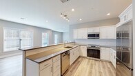 Located at 57 W Merritt Blvd in Fishkill, NY, this thoughtfully designed single-floor residence offers a clean, modern aesthetic with consistent finishes throughout. Light wood-tone flooring flows seamlessly across the living areas and bedrooms, complemented by neutral warm and cool gray wall tones that create a bright, welcoming atmosphere.

The kitchen is a standout feature, showcasing white shaker-style cabinetry, dark quartz countertops, a white subway tile backsplash, and a full suite of stainless steel appliances including a range, over-the-range microwave, dishwasher, and refrigerator. A peninsula with an overhang provides additional seating and defines the open-concept layout, while track lighting and recessed fixtures ensure well-lit workspaces. Multiple windows allow natural light to fill the kitchen and living areas.

The bedrooms are generously proportioned with ample natural light from large windows and light-toned flooring. The bathroom is finished with marble-look tile flooring, a soaking tub with a subway-tiled surround, and a gray vanity with a white countertop. A dedicated laundry room houses a full-size Samsung washer and dryer with overhead shelving. A clean hallway with gray modern doors connects the living spaces, completing this well-appointed, move-in-ready residence.