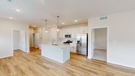 Located at 7230 Weymouth Way in Perrysburg, Ohio, this single-story home offers a well-designed layout across three bedrooms and two bathrooms. The open-concept kitchen and living area serves as the heart of the home, featuring light hardwood-style flooring that extends throughout the main living spaces. The kitchen is outfitted with white shaker cabinetry, a white subway tile backsplash, stainless steel appliances including a gas range, microwave, and refrigerator, and a central island with an undermount sink and light quartz countertops. Globe pendant lights add a modern finishing touch above the island. The living room offers generous natural light through multiple windows and includes a ceiling fan overhead. Three carpeted bedrooms provide comfortable retreats, with the primary bedroom offering direct access to an en-suite bathroom and closet. Both bathrooms feature wood-look flooring, white vanity cabinetry, and clean, neutral finishes; one includes a tub-shower combination with white tile surround. A utility room and two closets provide additional storage. The home's bright, neutral palette and consistent modern finishes create a cohesive and inviting atmosphere throughout.