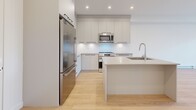 Located at 15624 24 Ave in Surrey, BC, this well-appointed two-bedroom, one-bathroom unit offers a clean, modern aesthetic throughout its thoughtfully designed single-floor layout. Light hardwood flooring flows seamlessly across every room, complementing the crisp white walls and creating a bright, cohesive ambiance.

The open-concept kitchen is a standout feature, showcasing flat-panel grey cabinetry extending to the ceiling for ample storage, quartz countertops, a central island with an undermount sink, and a full suite of stainless steel appliances including a refrigerator, electric range, built-in microwave, and dishwasher. Recessed lighting enhances the workspace.

The living room is spacious and airy, featuring a baseboard heating unit and clean, unobstructed walls ideal for flexible furniture arrangements. Both bedrooms are comfortably sized with light flooring and crisp white walls. The primary bedroom includes a wall-mounted air conditioning unit and sliding door access, while the second bedroom benefits from a large window with neighbourhood views and its own baseboard heater.

The bathroom is finished in a contemporary style with large-format floor tiles, a floating vanity with quartz countertop, a wide mirror, and a glass-enclosed shower. A dedicated closet completes this functional and modern space.
