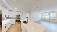 Located in Georgetown, TX, this well-designed single-story home offers three bedrooms, two bathrooms, and a thoughtfully planned open-concept layout. Light wood-style flooring flows consistently throughout the entire home, creating a cohesive and clean aesthetic.

The kitchen serves as the centerpiece of the living space, boasting a large central island with a quartz countertop and a matte black pull-down faucet over a bronze undermount sink. White shaker-style cabinetry with black hardware lines the walls, complemented by a subtle tile backsplash and a full suite of stainless steel appliances, including a gas range, microwave, dishwasher, and refrigerator. Built-in open shelving near the entry adds functional character.

The adjoining living area is bright and airy, benefiting from large windows with exterior views and a glass-panel entry door that fills the space with natural light.

The primary bedroom offers a comfortable footprint with a dedicated walk-in closet featuring built-in shelving and hanging rods. Additional bedrooms include closet space and windows that bring in natural light. The bathrooms are finished with white cabinetry, quartz countertops, matte black fixtures, and tile-surround tub-shower combinations. Recessed lighting throughout the home ensures consistent, modern illumination.