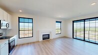 Located in Waukee, Iowa, this thoughtfully designed 2-bedroom, 2-bathroom home offers a clean, contemporary aesthetic throughout its single-floor layout. Light hardwood flooring flows seamlessly from room to room, complementing crisp white walls and modern black hardware and fixtures that appear as consistent design accents throughout the space.

The open-concept living room is a standout, featuring a sleek fireplace framed by a clean white surround and flanked by large black-framed grid windows that flood the space with natural light and offer sweeping views of the surrounding Iowa landscape. A glass sliding door provides access to a private balcony, extending the living area outdoors.

The kitchen is well-appointed with white shaker-style cabinetry reaching toward the ceiling, light quartz countertops, a subway tile backsplash, and a full suite of stainless steel appliances including a refrigerator, range, microwave, and dishwasher.

Both bedrooms are bright and comfortable, each with black-framed windows that frame open outdoor views and continue the home's modern design language. The bathrooms feature white vanities with quartz countertops and backlit mirrors with matte black towel ring accents. Additional conveniences include dedicated laundry, a hallway connecting the living areas, and ample closet storage throughout.