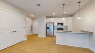Located at 9606 Lamont Ave in Cleveland, OH, this one-bedroom, one-bathroom unit offers a thoughtfully designed layout with modern finishes throughout. The open-concept living and kitchen area is anchored by light hardwood-style flooring that flows seamlessly through the main spaces, creating a bright and cohesive feel. The kitchen is well-equipped with white shaker cabinetry, granite-style countertops, a kitchen island with a sink, pendant lighting, and a full suite of stainless steel appliances including a side-by-side refrigerator with ice maker, electric range, and microwave. The living room benefits from a large sliding glass door dressed with vertical blinds, allowing an abundance of natural light to fill the space. The bedroom is carpeted for comfort, features a window with blinds, and connects to a spacious walk-in closet outfitted with wire shelving. The bathroom is clean and functional, offering a white vanity, a tub-shower combination, and brushed nickel fixtures. Recessed lighting throughout the unit adds a clean, contemporary touch. The overall aesthetic is neutral and modern, providing a versatile and move-in-ready living environment.