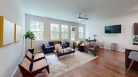 Located at 121 Marigny St in Moncks Corner, SC, this two-story home offers four bedrooms and three bathrooms spread across two thoughtfully designed floors. The main level opens with a welcoming entrance and a bright, open-concept living, dining, and kitchen area. The living room is bathed in natural light through a bank of large windows that frame lush greenery outside, complemented by warm hardwood flooring and a ceiling fan overhead. The kitchen is a functional standout, featuring rich dark wood cabinetry, granite countertops, stainless steel appliances, and generous workspace in a U-shaped layout. The dining area is adjacent, lit by a pendant chandelier and accented with clean, neutral walls. A hallway with recessed lighting connects the main living areas to additional rooms. The upper level houses the spacious primary bedroom, which benefits from natural light and serene outdoor views, alongside additional bedrooms and bathrooms finished with granite vanities, walk-in showers, and wood-look tile flooring. A dedicated laundry room with a full-size washer and dryer adds everyday convenience. Throughout, the home maintains a clean, modern aesthetic with neutral tones, white millwork, and consistent hardwood flooring, creating a cohesive and welcoming atmosphere.