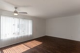 Located at 10913 Fruitland Dr in the Studio City neighborhood of Los Angeles, this single-floor unit offers a clean, modern aesthetic throughout. The open-concept layout connects the living area to the kitchen, creating a seamless flow across rich, dark hardwood flooring that runs throughout the main living spaces.

The living area is bright and airy, benefiting from large windows with vertical blinds that allow natural light to pour in. A ceiling fan adds practical comfort, while structural columns lend subtle architectural character to the space.

The kitchen features white cabinetry with contemporary hardware, sleek stone countertops with a subtle marble-like veining, and stainless steel appliances including an electric range, over-the-range microwave, and a stainless steel sink beneath a window. A wall-mounted air conditioning unit serves the main living area.

The bedroom is a well-proportioned, quiet retreat with the same hardwood flooring and a full-width mirrored sliding closet that enhances the sense of space and light.

The bathroom is finished in white tones, featuring a single vanity with an undermount sink, a large wall mirror, and a shower/tub combination, maintaining the clean and functional aesthetic found throughout the rest of the unit.
