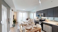Located at 2201 N Australian Ave in West Palm Beach, FL, this well-appointed 2-bedroom, 2-bathroom residence offers a thoughtfully designed single-floor layout. The open-concept living, dining, and kitchen area forms the heart of the home, bathed in natural light from large sliding glass doors that lead to a private balcony. The kitchen features dark espresso cabinetry that extends to the ceiling, stainless steel appliances including a range, microwave, and dishwasher, and granite countertops with a mirrored backsplash. Light wood-look flooring runs throughout the main living areas, complementing the bright, neutral palette. The primary bedroom offers a serene retreat with large windows, mirror-paneled walls, and ample closet space. The second bedroom is versatile and well-lit, featuring sheer curtains, built-in shelving, and a functional layout. Both bathrooms are finished with granite vanity countertops and dark wood cabinetry; the full bath includes a soaking tub with shower. Four closets and an in-unit laundry area provide generous storage. The overall ambiance is clean, contemporary, and efficient, making excellent use of a compact yet functional floor plan.