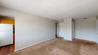 Located at 9060 E 39th Pl in Indianapolis, Indiana, this single-floor, 2-bedroom, 1-bathroom home offers a practical and efficient layout. The living room is generously sized, featuring warm beige carpeting, neutral gray walls, a textured ceiling, and a sliding glass door that invites natural light and provides outdoor access. The kitchen is equipped with warm honey-toned wood cabinetry, granite-style countertops, a white gas range, and hardwood flooring, creating a functional cooking space. The primary bedroom is a comfortable size, with carpeted flooring, a window for natural light, and access to a closet. The second bedroom mirrors a similar design with carpeting, neutral walls, and its own closet space — notably featuring two closet doors for added storage. The full bathroom includes a tub-shower combination with a tiled surround and curved curtain rod. Throughout the home, four closets provide excellent storage capacity, complemented by a dedicated utility room. A connecting hallway ties the rooms together seamlessly. The consistent use of neutral tones and carpet throughout the living spaces contributes to a cohesive, move-in ready ambiance.