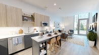 Located on Inspiration Street in Reston, Virginia, this thoughtfully designed one-bedroom, one-bathroom residence offers a modern aesthetic throughout its efficiently organized single-floor layout. Light wood-tone flooring flows continuously through every room, creating a cohesive and airy feel.

The open-concept kitchen and living area forms the heart of the home. The kitchen is outfitted with two-tone cabinetry — warm wood uppers paired with charcoal lowers — white quartz countertops, a white tile backsplash, and a full suite of stainless steel appliances including a French door refrigerator, range, and built-in microwave. A central island with seating provides additional prep space and casual dining.

The living room is anchored by floor-to-ceiling windows and a glass door that floods the space with natural light and offers views of the surrounding Reston streetscape. The bedroom is a comfortable retreat with a dedicated walk-in closet featuring built-in shelving and hanging storage. The full bathroom includes a soaking tub and shower combination with large-format gray tile surround, a single-sink vanity with quartz countertop, and light wood flooring that ties the space together. Clean lines and neutral tones define the overall ambiance throughout.