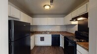 This single-floor, 2-bedroom, 2-bathroom residence offers a practical and comfortable layout designed to maximize livability. The open living area features rich, dark wood-style flooring that flows seamlessly throughout the main spaces, complemented by neutral wall tones and a textured ceiling. Natural light filters in through windows, and recessed lighting adds warmth to the interior. The living space connects directly to an exterior door, providing convenient access.

The kitchen is thoughtfully designed in a U-shaped configuration, featuring white cabinetry with ample upper and lower storage, dark laminate countertops, and a full suite of black appliances including a refrigerator, electric range, and dishwasher. Dark hardwood-style flooring continues through this space, adding a cohesive feel.

Both bedrooms are generously sized and finished with plush, neutral-toned carpeting. Each room benefits from natural light through windows and recessed ceiling fixtures, offering a restful and versatile environment.

The two bathrooms each have distinct features: one includes a wide vanity with a speckled countertop and a large mirror, while the second features a classic tiled tub-shower combination. Both are finished with hardwood-style flooring and clean, minimal fixtures, providing everyday functionality.