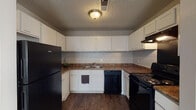 This single-floor, 2-bedroom, 2-bathroom residence offers a practical and comfortable layout designed to maximize livability. The open living area features rich, dark wood-style flooring that flows seamlessly throughout the main spaces, complemented by neutral wall tones and a textured ceiling. Natural light filters in through windows, and recessed lighting adds warmth to the interior. The living space connects directly to an exterior door, providing convenient access.

The kitchen is thoughtfully designed in a U-shaped configuration, featuring white cabinetry with ample upper and lower storage, dark laminate countertops, and a full suite of black appliances including a refrigerator, electric range, and dishwasher. Dark hardwood-style flooring continues through this space, adding a cohesive feel.

Both bedrooms are generously sized and finished with plush, neutral-toned carpeting. Each room benefits from natural light through windows and recessed ceiling fixtures, offering a restful and versatile environment.

The two bathrooms each have distinct features: one includes a wide vanity with a speckled countertop and a large mirror, while the second features a classic tiled tub-shower combination. Both are finished with hardwood-style flooring and clean, minimal fixtures, providing everyday functionality.
