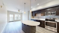Located at 450 Tenth Avenue in San Diego, CA, this well-appointed 2-bedroom, 2-bathroom residence offers a thoughtfully designed single-level floor plan. The open-concept living area seamlessly integrates the kitchen, dining, and living spaces, creating a bright and cohesive environment. Light wood-tone flooring runs throughout, complementing the neutral color palette and modern finishes.

The kitchen is a standout feature, boasting rich dark cabinetry, a full suite of stainless steel appliances including a refrigerator, range, microwave, and dishwasher, a tiled backsplash, and a curved center island with pendant lighting overhead — ideal for both cooking and casual dining. A ceiling fan anchors the living area, which opens directly to a private balcony through a glass-panel door, allowing natural light to fill the space.

Both bedrooms are generously proportioned, featuring large windows with urban views and ample closet space. The bathrooms are finished with clean, contemporary tile work, including a full soaking tub and shower combination. Additional conveniences include in-unit laundry and multiple hallway closets for added storage. This residence offers a polished, move-in-ready living experience in the heart of San Diego.