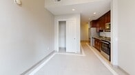Located at 1249 Griswold in the heart of downtown Detroit, this efficiently designed studio unit makes excellent use of its compact footprint. The open living area features clean, neutral-toned large-format tile flooring accented by a distinctive hexagonal mosaic tile border, lending a polished, contemporary feel to the space. Recessed lighting illuminates the room, while large windows frame views of the surrounding Detroit skyline, filling the space with natural light.

The galley-style kitchen is a standout feature, outfitted with rich dark-wood cabinetry that extends floor to ceiling for generous storage. A full suite of stainless steel appliances — including a refrigerator, electric range, built-in microwave, dishwasher, and sink — makes the kitchen both functional and visually striking. Neutral countertops complement the warm wood tones throughout.

A sliding-door closet provides convenient storage within the main living area. The bathroom continues the refined aesthetic with consistent tile flooring, a wood-accented vanity with a quartz-style countertop, and a glass-enclosed walk-in shower with full tile surround, offering a clean and modern finish. The overall design throughout the unit is cohesive, practical, and well-appointed for urban living in downtown Detroit.