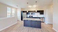 Located at 2925 Countrywood Parkway in Memphis, TN, this single-floor residence offers a well-designed layout ideal for comfortable everyday living. The open-concept kitchen and living area serves as the heart of the home, featuring light hardwood-style flooring, neutral warm-gray walls, and an abundance of natural light from multiple windows. The kitchen is appointed with dark espresso cabinetry, granite countertops, a subway tile backsplash, stainless steel appliances including a French door refrigerator, and a large center island with pendant lighting overhead — perfect for both meal preparation and casual dining. A built-in desk nook and a glass door providing outdoor access add functional versatility to the living area. The spacious bedroom is carpeted for comfort, equipped with a ceiling fan, and features windows with views of the surrounding landscape. A dedicated closet provides ample storage. The bathroom is finished with a granite-topped dark vanity, a large wall mirror, and a full tub-shower combination with clean white tiling. Throughout the space, consistent finishes and a cohesive neutral color palette create a modern, move-in-ready atmosphere.