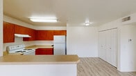 Located in Wickenburg, Arizona, this single-floor residence offers three bedrooms and three bathrooms with a practical and cohesive layout. The kitchen is a standout feature, equipped with rich wood cabinetry, a U-shaped countertop layout with a double sink, a built-in range, dishwasher, and refrigerator. The kitchen opens to the main living area through a peninsula counter, creating a connected and functional space. Light wood-style flooring runs throughout the main living and kitchen areas, contributing to a clean, bright aesthetic.

The bedrooms are carpeted and filled with natural light, with the primary bedroom featuring a wide window overlooking the surrounding desert landscape with native vegetation — a serene view characteristic of the Arizona setting. Bedrooms include sliding mirrored closet doors, adding a practical touch.

Each of the three bathrooms follows a consistent design language, featuring warm wood vanities with light countertops, large vanity mirrors with overhead lighting strips, and light wood-style flooring. Select bathrooms include a combined shower and tub. The overall design is clean and neutral, with white walls throughout providing a bright, open feel ideal for comfortable living in the Wickenburg desert community.