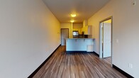 This single-floor unit offers a practical and comfortable layout with a clean, modern aesthetic carried throughout each area. The open-concept living and kitchen space serves as the heart of the unit, where wood-look laminate flooring flows seamlessly underfoot. The kitchen is equipped with stainless steel appliances, including a refrigerator, electric range, and over-the-range microwave, all complemented by light maple cabinetry and speckled granite-style countertops. A peninsula with bar seating provides additional prep space and separates the kitchen from the living area, making the layout ideal for everyday functionality.

The living area benefits from a sliding glass door fitted with vertical blinds, opening to a private balcony that overlooks lush greenery, filling the space with natural light. The bedroom continues the wood-look flooring and features a large window with vertical bar detailing, offering pleasant outdoor views and ample natural illumination.

The bathroom is well-appointed with a wide granite-style vanity countertop, light maple cabinetry with brushed nickel hardware, a large mirror, and an additional wall-mounted medicine cabinet. A full soaking tub and shower combo with a clean white surround completes the bathroom. Throughout the unit, neutral wall tones and dark baseboards create a cohesive and inviting atmosphere.