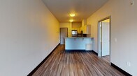 This single-floor unit offers a practical and comfortable layout with a clean, modern aesthetic carried throughout each area. The open-concept living and kitchen space serves as the heart of the unit, where wood-look laminate flooring flows seamlessly underfoot. The kitchen is equipped with stainless steel appliances, including a refrigerator, electric range, and over-the-range microwave, all complemented by light maple cabinetry and speckled granite-style countertops. A peninsula with bar seating provides additional prep space and separates the kitchen from the living area, making the layout ideal for everyday functionality.

The living area benefits from a sliding glass door fitted with vertical blinds, opening to a private balcony that overlooks lush greenery, filling the space with natural light. The bedroom continues the wood-look flooring and features a large window with vertical bar detailing, offering pleasant outdoor views and ample natural illumination.

The bathroom is well-appointed with a wide granite-style vanity countertop, light maple cabinetry with brushed nickel hardware, a large mirror, and an additional wall-mounted medicine cabinet. A full soaking tub and shower combo with a clean white surround completes the bathroom. Throughout the unit, neutral wall tones and dark baseboards create a cohesive and inviting atmosphere.