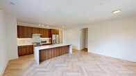 Located at 100 East Putnam Avenue in Greenwich, CT, this thoughtfully designed 2-bedroom, 2-bathroom residence showcases high-end finishes and a cohesive modern aesthetic throughout its single-floor layout. The open-concept living, dining, and kitchen area serves as the heart of the home, featuring striking herringbone-patterned light hardwood floors, crisp white walls, and black-framed grid windows that invite natural light and garden views. The chef's kitchen is appointed with rich walnut cabinetry, a waterfall-edge white quartz island with an integrated sink and brushed gold faucet, stainless steel appliances, and track lighting overhead. Both bathrooms are finished to a high standard with handmade-style square ceramic tile, floating walnut vanities topped with white quartz, arched gold-framed mirrors, and brushed gold fixtures throughout. One bathroom features a glass-enclosed walk-in shower, while the second offers a tiled soaking tub. The bedrooms are bright and serene, each with black-framed windows overlooking greenery. Ample storage is provided by four closets, including a well-organized walk-in with built-in shelving and chrome hanging rods. A dedicated hallway system and utility room round out this refined and well-appointed residence.