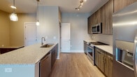 Located at 9200 Bruckhaus St in Raleigh, NC, this single-floor residence offers a thoughtfully designed open-concept layout that seamlessly connects the kitchen, dining, and living areas. The kitchen is well-appointed with rich dark wood cabinetry, granite countertops, a central island with a built-in sink, and a full suite of stainless steel appliances including a refrigerator, range, microwave, and dishwasher. Track lighting and pendant fixtures illuminate the space with a modern flair. The spacious living area features wood-look flooring, a ceiling fan, and glass French doors that invite natural light and provide outdoor access. Two bedrooms are finished with plush carpeting and ceiling fans; one includes a window with exterior views, while the other offers a quiet, neutral retreat. The primary bathroom is generously sized with a granite-topped vanity, built-in open shelving, a glass-enclosed shower, and direct access to a walk-in closet. The secondary bathroom features a tub-shower combination and a matching dark wood vanity with granite counters. A dedicated laundry room houses a full-size top-loading washer and dryer with overhead shelving, adding everyday convenience to this polished Raleigh residence.
