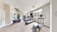 Located at 1724 Robb St in Lakewood, Colorado, this 24-hour fitness center offers a thoughtfully organized workout space designed to accommodate a full range of exercise routines. The single-floor gym is finished with neutral, light-toned walls and low-pile patterned carpeting that gives the space a clean, professional appearance. Vaulted ceilings in portions of the room add a sense of openness, while multiple large windows along the perimeter flood the interior with natural light and provide views of the surrounding greenery outdoors.

The cardio zone is well-stocked with a lineup of Spirit treadmills, elliptical trainers, and a stationary bike, all arranged to take advantage of the natural light from the windows. A wall-mounted flat-screen television is positioned for easy viewing during cardio sessions. The strength training area features multi-function cable and weight machines, along with a dedicated free weights section equipped with a dumbbell rack and an adjustable workout bench. A large mirror panel is mounted along one wall to support proper form during exercise.

The facility includes a direct exterior entrance with a coat hook area, posted gym rules, and an emergency exit, ensuring convenience and safety for all users. The overall ambiance is bright, functional, and inviting — well-suited for daily fitness use.