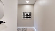Located on the fourth floor at 1324 N Capitol St NW in Washington, DC, this one-bedroom, one-bathroom unit offers a thoughtfully designed layout with modern finishes throughout. The open-concept living area seamlessly connects the kitchen and dining space, creating an efficient and welcoming environment. Light wood-tone flooring runs throughout, complementing the neutral white walls and contributing to a bright, airy feel. The kitchen is outfitted with sleek flat-front cabinetry in a warm taupe finish, stainless steel appliances including a refrigerator, range, and built-in microwave, as well as a clean-lined countertop workspace. A cozy dining area sits adjacent, ideal for casual meals. The bedroom features high clerestory windows that allow natural light to filter in while maintaining privacy, with light wood floors and minimalist wall sconces lending a calm, restful ambiance. A hallway connects the main living areas to the full bathroom, which is finished with large-format stone-look tile flooring, a tub-shower combination with marble-patterned tile surround, a wall-mounted vanity with a warm wood finish, and crisp white walls. The overall design aesthetic is clean, contemporary, and functional, making this a well-appointed urban residence in the heart of the nation's capital.
