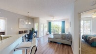 Located at 244 Three Islands Blvd in Hallandale Beach, Florida, this well-appointed single-floor residence offers a thoughtfully designed open-concept layout that promotes a natural flow between living spaces. The combined living and dining area is bathed in natural light from large sliding glass doors that lead to a private balcony overlooking lush greenery. Wood-look flooring runs throughout the main living areas, complemented by textured ceilings and neutral-toned walls that create a clean, contemporary ambiance. A ceiling fan keeps the living space comfortable year-round.

The kitchen is a standout feature, showcasing white shaker-style cabinetry, quartz countertops, a mosaic tile backsplash, and a full suite of stainless steel appliances including a refrigerator, range, microwave, and dishwasher. A breakfast bar with stylish bar seating connects the kitchen seamlessly to the living area.

The bedrooms offer plush carpeting, ample closet space, and natural light from window treatments. One bedroom includes a walk-in closet with built-in shelving. The bathrooms are well-appointed with wood-look flooring, vanities with quartz countertops, and glass-enclosed showers. The overall design balances comfort and modern finishes throughout.