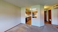 Located at 3510 W 53rd St in Sioux Falls, South Dakota, this single-floor unit offers a practical and straightforward layout. The kitchen is a standout functional space, featuring warm oak cabinetry—both upper and lower—that wraps around an L-shaped configuration, providing ample storage throughout. Light-colored countertops offer generous workspace, complemented by a double stainless steel sink, built-in appliances including a microwave, range, and refrigerator, and durable hard-surface flooring. A pass-through opening connects the kitchen to the adjacent living area, creating an open sightline between the two spaces.

The living area is spacious and carpeted, with neutral-toned walls and a textured ceiling. A pair of windows along one wall allows natural light to filter in, offering views of the surrounding greenery. The overall feel is open and versatile.

The bedrooms are carpeted and well-proportioned, each featuring a window for natural light and access to closet storage with built-in rods. The bathroom includes a full tub and shower surround with chrome fixtures, a toilet, and wood-look flooring, keeping the space clean and functional. Dark-stained wood trim and doors appear consistently throughout, lending a cohesive, classic character to the interior.