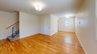 Located in Portland, Oregon, this 2-bedroom, 1-bathroom home spans three floors, offering a well-organized layout with dedicated spaces for living, sleeping, and storage. The main living level features a generously sized living room with warm hardwood flooring, neutral walls, and multiple windows that invite natural light throughout. The kitchen is a standout space, appointed with white shaker-style cabinetry, tile countertops with dark accent edging, stainless steel appliances including a refrigerator, dishwasher, and electric range, and a classic black-and-white checkered floor that adds a timeless character. The upper floor houses both bedrooms, each finished with gleaming hardwood floors and bright windows offering views of the surrounding neighborhood. The primary bedroom is notably spacious and includes multiple closet access points. The shared full bathroom features a white vanity with stone-style countertop, a tub-shower combination, and a window for natural ventilation. The lower level provides a utility and storage area with a painted concrete floor and staircase access, offering practical flexibility. With four closets throughout, storage is plentiful in this thoughtfully laid-out Portland home.