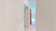 Located in Chicago's vibrant West Loop neighborhood, this modern 2-bedroom, 1-bathroom residence offers a thoughtfully designed single-floor layout with clean, contemporary finishes throughout. Light-toned hardwood flooring runs seamlessly across every room, complementing the crisp white walls and recessed lighting that create a bright, airy atmosphere.

The open-plan kitchen serves as the centerpiece of the living space, featuring a striking waterfall island with a marble-look quartz countertop and warm wood-grain paneling. Sleek white upper cabinetry contrasts with walnut-toned accents, while stainless steel appliances — including a French door refrigerator, built-in microwave, and gas range — complete the chef-ready setup. A linear pendant light adds a modern touch overhead.

The primary bedroom is generously proportioned, offering floor-to-ceiling sliding glass doors that open to a private balcony with city views, flooding the room with natural light. The second bedroom features a sliding panel door and access to the bathroom. The hallway connects the rooms cleanly, with panel-style doors and a minimalist aesthetic maintained throughout.

The bathroom is finished with a wide quartz vanity, large wall mirror, textured tile walk-in shower, and light wood cabinetry — combining functionality with a spa-like feel.