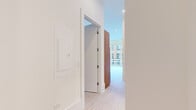 Located in Chicago's vibrant West Loop neighborhood, this modern 2-bedroom, 1-bathroom residence offers a thoughtfully designed single-floor layout with clean, contemporary finishes throughout. Light-toned hardwood flooring runs seamlessly across every room, complementing the crisp white walls and recessed lighting that create a bright, airy atmosphere.

The open-plan kitchen serves as the centerpiece of the living space, featuring a striking waterfall island with a marble-look quartz countertop and warm wood-grain paneling. Sleek white upper cabinetry contrasts with walnut-toned accents, while stainless steel appliances — including a French door refrigerator, built-in microwave, and gas range — complete the chef-ready setup. A linear pendant light adds a modern touch overhead.

The primary bedroom is generously proportioned, offering floor-to-ceiling sliding glass doors that open to a private balcony with city views, flooding the room with natural light. The second bedroom features a sliding panel door and access to the bathroom. The hallway connects the rooms cleanly, with panel-style doors and a minimalist aesthetic maintained throughout.

The bathroom is finished with a wide quartz vanity, large wall mirror, textured tile walk-in shower, and light wood cabinetry — combining functionality with a spa-like feel.