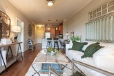 This thoughtfully designed single-floor residence blends rustic charm with modern convenience across its key living spaces. The bedroom serves as a standout retreat, anchored by a striking four-poster bed crafted from weathered wood, complemented by light carpet, a patterned area rug, and natural light streaming in through large windows. The warm ambiance is enhanced by tasteful artwork and industrial-style accent lighting.

The kitchen is fully equipped for everyday living, featuring warm honey-toned cabinetry, granite countertops, and a complete suite of stainless steel appliances including a refrigerator, range, microwave, and dishwasher. A peninsula with bar seating and pendant lighting creates a natural gathering point, while hardwood flooring and track lighting add to the functional, inviting atmosphere.

The living area exudes a relaxed, eclectic character, with crown molding, hardwood floors, and a set of French doors that open to an outdoor space, flooding the room with natural light. Vintage-inspired wall décor and a textured area rug contribute to the space's warm, layered aesthetic.

The bathroom is finished with granite-topped cabinetry, warm wood vanity storage, tile flooring, and a tub-shower combination with a decorative mosaic tile border, providing a clean and comfortable layout throughout.
