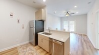 Located in Burlington, NC, this 2-bedroom, 1-bathroom residence offers a thoughtfully designed single-floor layout that makes efficient use of its cozy footprint. The open kitchen is a standout feature, equipped with stainless steel appliances including a refrigerator, dishwasher, range, and microwave. Light taupe cabinetry, white countertops, and light hardwood-style flooring give the kitchen a clean, contemporary feel, while a peninsula with a sink creates a natural connection to the living area beyond. A ceiling fan overhead and a window overlooking the outdoors add comfort and natural light to the shared living space.

The two bedrooms are carpeted and bright, each benefiting from natural light through well-positioned windows. The primary bedroom is generously proportioned and includes a ceiling fan for year-round comfort. A secondary bedroom features direct access to a dedicated closet with built-in shelving, providing practical storage. A carpeted hallway connects the bedrooms to the full bathroom, which features a tub-shower combination with a curved curtain rod, a vanity with cabinet storage, and hardwood-style flooring. The neutral color palette throughout — soft whites and warm grays — lends the entire space a clean, move-in-ready ambiance.