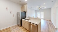 Located in Burlington, NC, this 2-bedroom, 1-bathroom residence offers a thoughtfully designed single-floor layout that makes efficient use of its cozy footprint. The open kitchen is a standout feature, equipped with stainless steel appliances including a refrigerator, dishwasher, range, and microwave. Light taupe cabinetry, white countertops, and light hardwood-style flooring give the kitchen a clean, contemporary feel, while a peninsula with a sink creates a natural connection to the living area beyond. A ceiling fan overhead and a window overlooking the outdoors add comfort and natural light to the shared living space.

The two bedrooms are carpeted and bright, each benefiting from natural light through well-positioned windows. The primary bedroom is generously proportioned and includes a ceiling fan for year-round comfort. A secondary bedroom features direct access to a dedicated closet with built-in shelving, providing practical storage. A carpeted hallway connects the bedrooms to the full bathroom, which features a tub-shower combination with a curved curtain rod, a vanity with cabinet storage, and hardwood-style flooring. The neutral color palette throughout — soft whites and warm grays — lends the entire space a clean, move-in-ready ambiance.