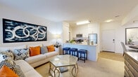 Located at 4914 Olive St in Montclair, CA, this well-designed one-bedroom, one-bathroom residence offers a thoughtfully organized single-floor layout. The open-concept living and kitchen area forms the heart of the home, where the kitchen features crisp white cabinetry, stainless steel appliances including a refrigerator, microwave, and range, and a peninsula with bar seating — ideal for casual dining or entertaining. Warm hardwood-style flooring flows through the kitchen and entry areas, transitioning to plush carpet in the living room and bedroom. The living room is bright and welcoming, with large windows that invite natural light and provide views of the surrounding greenery. A dedicated entry foyer provides a clean transition into the living space. The bedroom is a comfortable retreat, offering ample space, multiple windows with natural light, and access to a closet. A hallway connects the main areas to the full bathroom, which features a clean, white tub-shower combination with warm wood-tone flooring. The overall ambiance is modern and inviting, with a neutral palette that lends itself well to personalization throughout this efficient and functional Montclair residence.