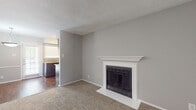 This single-floor residence offers a practical and comfortable layout across several well-defined living spaces. The living room serves as the centerpiece of the home, highlighted by a wood-burning fireplace framed with a classic white mantel and surround, set against neutral gray walls and soft wall-to-wall carpeting. A window allows natural light to brighten the space, creating a welcoming atmosphere.

The kitchen is a functional galley-style space equipped with rich dark-stained cabinetry, granite-look countertops, a mosaic tile backsplash, and a full suite of black appliances including a range and refrigerator. Wood-look flooring runs throughout the kitchen, adding warmth and contrast to the darker cabinetry.

The bedrooms are carpeted and neutrally finished, each offering closet storage with built-in shelving. One bedroom features a ceiling fan and a window with outdoor views, while another connects directly to a bathroom for added convenience.

The bathroom includes a full tub and shower combination with clean white surrounds, wood-look flooring, and straightforward, functional fixtures. Textured ceilings are consistent throughout the home, contributing to its understated, move-in-ready character.