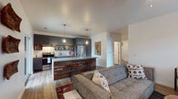 Located on NW A St in Bentonville, Arkansas, this single-floor unit blends modern design with warm, industrial-inspired touches throughout. The open-concept layout connects the living, dining, and kitchen areas into one cohesive and functional space. The kitchen is a standout feature, showcasing slate-gray cabinetry, a classic white subway tile backsplash, stainless steel appliances, and a kitchen island clad in reclaimed wood with bar seating — all illuminated by stylish pendant lighting. Wood-look flooring runs throughout the entire unit, lending warmth and continuity to every room. The living area is bright and welcoming, with a large window inviting natural light and providing views of the surroundings. A dedicated dining nook adjacent to the living space offers additional flexibility. The bedroom is comfortably sized, featuring a ceiling fan and a window that fills the room with natural light. A versatile secondary room serves well as a home office or flex space, also with a window. The full bathroom is clean and well-appointed, with white cabinetry and a shower-tub combination. A dedicated laundry area houses a stacked washer and dryer unit alongside an organized walk-in closet with built-in shelving, rounding out this well-designed and practical living space.