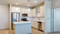 Located at 1155 Park Ln in Davenport, Florida, this single-floor residence offers a clean, contemporary design with a bright and cohesive aesthetic throughout. The open-concept layout connects the kitchen and living area seamlessly, creating a welcoming and functional living environment. Light-toned luxury vinyl plank flooring runs throughout the entire space, enhancing the sense of openness and continuity.

The kitchen is a standout feature, equipped with stainless steel appliances including a French door refrigerator, electric range, over-the-range microwave, and dishwasher. Crisp white cabinetry, a classic subway tile backsplash, and quartz countertops provide a polished look, while a central island offers additional prep space and storage. Pendant lighting and recessed fixtures illuminate the area effectively. Ceiling fans are present in the living area and bedrooms for added comfort.

The bedrooms are well-proportioned, featuring walk-in closets with wire shelving systems and ample natural light from large windows. The primary bathroom includes a walk-in shower with tile surround and a vanity with quartz countertops, while the secondary bathroom features a tub-shower combination. Both bathrooms maintain the same light, neutral palette found throughout the home, contributing to the space's overall modern and inviting character.