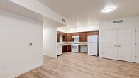 Located at 1335 W Luchessa Avenue in Gilroy, California, Unit 108 is a thoughtfully designed single-floor residence that combines functional living with a clean, modern aesthetic. Light wood-style flooring runs continuously throughout the unit, lending warmth and visual cohesion to every room.

The open-concept living area is bright and welcoming, featuring neutral cream-toned walls, ceiling-mounted lighting, and multiple HVAC vents for year-round comfort. A glazed exterior door with an adjacent window fills the living space with natural light and provides direct access to the outdoors.

The kitchen is well-appointed with rich warm-toned wood cabinetry, ample upper and lower storage, light countertops, and a full suite of white appliances including a gas range, dishwasher, and refrigerator. Recessed lighting above the kitchen adds a polished finish to the space.

The bedroom includes a spacious double-door closet, while an additional room with a walk-in closet area featuring built-in shelving provides versatile storage or flexible use. The bathroom is designed with accessibility in mind, featuring grab bars, an open layout, and wide clearances throughout.

Overall, the unit presents a clean, move-in ready environment with practical features suited for comfortable, accessible everyday living.