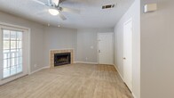 Located at 5206 Village Crest Way in Knoxville, Tennessee, this single-floor, two-bedroom, two-bathroom home offers a practical and comfortable layout. The combined living and dining area serves as the heart of the home, featuring plush carpeting, a ceiling fan, a tile-surround wood-burning fireplace, and a glass door that opens to a private balcony — bringing in natural light and outdoor views. The kitchen is efficiently designed with wood-trimmed cabinetry, dark countertops, a double sink, and wood-look flooring, providing ample storage and workspace. Both bedrooms are carpeted and feature natural light from windows, neutral wall tones, and built-in bifold closets, offering a calm and restful atmosphere. The spacious primary bedroom includes its own dedicated closet space. Both bathrooms are identically appointed with wood-trimmed vanities, dark granite-style countertops, large mirrors, and a tub-shower combination with tile surround, set on light wood-look flooring. The home also includes a dedicated laundry area and three closets throughout, enhancing everyday functionality. Textured ceilings are consistent throughout the home, adding a classic residential character.