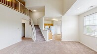 Located at 422 Eagle Pointe Dr in Canonsburg, PA, this three-bedroom, three-bathroom multi-level home offers a well-organized layout spread across three floors. The main living level serves as the heart of the home, featuring an open-concept living room and kitchen. The living room impresses with dramatic vaulted ceilings, a tiled fireplace flanked by large windows that invite abundant natural light, and plush wall-to-wall carpeting. A ceiling fan adds comfort to the airy space. The kitchen is equipped with warm honey-toned cabinetry, granite-look countertops, white appliances including a gas range, built-in microwave, refrigerator, and dishwasher, all set atop light hardwood-style flooring. Each of the three bathrooms features hardwood-style flooring, warm wood vanities with white countertops, and a tub-shower combination. The generously sized primary bedroom includes a ceiling fan and plush carpeting. An open upper-level loft area overlooks the main living space, accessible via carpeted staircases with white railings. The home also includes a utility room, multiple closets for ample storage, and an attached single-car garage with an automatic opener. The overall aesthetic is clean, neutral, and move-in ready.