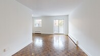 Located at 49 McMurchy Ave N in Brampton, Ontario, this one-bedroom, one-bathroom unit offers a well-organized layout across a single floor. The combined living and dining area is one of the most notable spaces, featuring gleaming parquet wood floors in a classic checkerboard pattern, bright white walls, and large windows that draw in generous natural light. A sliding glass door provides direct access to an outdoor area, enhancing the sense of openness. Baseboard heating is present throughout, ensuring comfort year-round. The galley-style kitchen is efficiently designed with white shaker cabinetry extending to the ceiling, subway tile backsplash, dark countertops, and a full suite of stainless steel appliances including a refrigerator, electric range, and over-the-range microwave. Large-format tile flooring completes the clean, modern look of the kitchen. The bedroom is a comfortable, quiet retreat with the same distinctive parquet flooring, a window with outdoor views, and a mirrored sliding-door closet that adds both storage and a sense of depth. The bathroom features a full soaking tub framed by crisp white subway tile, offering a clean and timeless aesthetic.