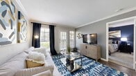 Located at 450 El Dorado Blvd in Houston, TX, this 2-bedroom, 1-bathroom residence offers a thoughtfully designed layout across a single level. The living room is a welcoming focal point, featuring crown molding, dark hardwood-style flooring, and multiple windows dressed with bold navy drapes that invite generous natural light. A glass-top coffee table and vibrant area rug add contemporary flair to the comfortable seating area.

The kitchen is well-equipped with white raised-panel cabinetry, granite-style countertops, a gray subway tile backsplash, and stainless steel appliances including a refrigerator and electric range. A peninsula counter with bar stool seating creates a practical casual dining option and connects the kitchen seamlessly to the living area.

The primary bedroom features a bold navy accent wall, ceiling fan, and plush carpeting, providing a cozy retreat. The second bedroom is bright and airy, with natural light filtering through a window framed by navy curtains. The bathroom offers a spacious vanity with a granite-style countertop, a framed mirror, and clean, neutral finishes throughout.

Dark hardwood-style flooring flows through the main living spaces, tying the home together with a cohesive, modern aesthetic.