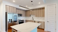 This contemporary 1060 square foot apartment, located at 10 Tower Rd NW in Atlanta, Georgia, offers a harmonious blend of style and functionality. The space comprises two bedrooms, including a generous 220 square foot primary bedroom, and two bathrooms, all designed with modern living in mind.

The heart of the home is a sleek, open-concept kitchen featuring wood-toned cabinetry, stainless steel appliances, and a large island with built-in wine storage. The kitchen's light quartz countertops and linear lighting create a bright, inviting atmosphere.

Throughout the apartment, warm wood-toned flooring contrasts beautifully with crisp white walls, creating a sense of warmth and spaciousness. The living areas are thoughtfully designed, with ample natural light flowing through large windows, some offering city views.

Both bedrooms are well-proportioned, with the primary bedroom boasting a ceiling fan for added comfort. The bathrooms continue the modern aesthetic with clean lines, floating vanities, and contemporary fixtures.

Storage is a key feature, with two closets equipped with efficient shelving systems. The apartment also includes a hallway, adding to the sense of space and flow. Overall, this apartment offers a perfect balance of style, comfort, and practicality in the heart of Atlanta.