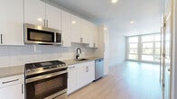 Located at 833 Summer St in Stamford, Connecticut, this thoughtfully designed one-bedroom, one-bathroom residence offers a clean, modern aesthetic across a well-organized single floor. Light wood-toned flooring runs throughout, complementing the bright, neutral palette that defines every room.

The open-concept living area flows seamlessly from the kitchen toward oversized floor-to-ceiling windows that flood the space with natural light and frame views of the surrounding neighborhood. The kitchen is well-appointed with sleek white cabinetry, stainless steel appliances including a gas range, built-in microwave, and refrigerator, along with a subway tile backsplash and a undermount sink — a functional and stylish space for everyday cooking.

The bedroom is generously proportioned, featuring a large grid-pane window that continues the home's bright, airy feel. An organized walk-in closet with built-in shelving, hanging rods, drawers, and dedicated shoe storage provides ample and efficient storage solutions.

The bathroom is finished to a high standard, showcasing large-format marble-look tile surrounding the soaking tub and shower, a backlit LED vanity mirror, white cabinetry with quartz countertop, and neutral floor tile — creating a clean, spa-inspired atmosphere. The overall design of this residence balances modern style with practical livability.