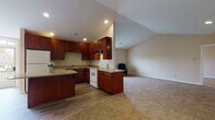 Located at 5561 Waterford Cir in Sheffield, Ohio, this single-floor residence offers a well-designed open-concept layout that seamlessly connects the kitchen and living areas. The kitchen is a standout feature, showcasing rich dark-wood cabinetry extending to the ceiling for generous storage, granite-topped counters, a central island with additional workspace, and wood-style flooring. White appliances including a range, dishwasher, and refrigerator are neatly integrated throughout. Recessed lighting illuminates the space, while a large arched window at the far end of the kitchen admits natural light and provides a view to the outdoor deck beyond.

The adjoining living area transitions to plush carpeting and benefits from vaulted ceilings that lend an airy, open feel. Multiple windows supply natural light throughout. The bedrooms are carpeted and comfortably proportioned, each featuring windows that bring in additional daylight. The bathroom is finished with rich wood vanity cabinetry, a framed mirror, and a glass-door walk-in shower with wood-style flooring, delivering a clean and functional aesthetic throughout the home.