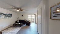 This single-story residence offers a thoughtfully designed layout across multiple rooms, each finished with consistent, neutral tones and durable wood-look flooring throughout the main living areas. The living room serves as the central gathering space, featuring a ceiling fan, a sliding glass door that opens to an outdoor patio, and ample room for comfortable seating. Adjacent to the living room, a dedicated dining area provides space for a full dining set, seamlessly connecting to the rest of the home. The kitchen is well-equipped with white cabinetry, granite-style countertops, black appliances including a refrigerator, range, microwave, and dishwasher, along with a double sink — all set on light wood-look flooring. The bedrooms are carpeted for comfort, each outfitted with a ceiling fan and closet storage. The primary bedroom includes a window allowing natural light to fill the space. The bathrooms feature granite-style vanity countertops, mirrored medicine cabinets, and wood-look tile flooring, with one bathroom offering a shower and the other a shower-tub combination. Textured ceilings are consistent throughout, adding a classic character to the home's overall clean and functional aesthetic.