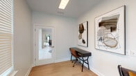 Located at 7405 Outer Loop in Louisville, Kentucky, this single-story space presents a clean, contemporary aesthetic throughout its well-appointed interior. Light wood flooring flows consistently across the space, complementing the soft neutral wall tones that create a calm, professional atmosphere.

The space includes a dedicated office area, furnished with a sleek black writing desk and a leather chair. Large windows fitted with horizontal blinds allow ample natural light to filter in while maintaining privacy. Abstract artwork adorns the walls, adding a curated, modern touch to the workspace. A glass-paneled interior door connects this area to adjacent spaces, maintaining a sense of openness and visual continuity.

A lounge area serves as a welcoming entry point, featuring a pair of low-profile leather chairs accented with warm amber cushions, arranged around a geometric white side table atop a woven area rug. Contemporary abstract artwork lines the walls, reinforcing the modern design language. A full-glass exterior door opens to views of lush greenery, bringing in natural light and a connection to the outdoors. The space is equipped with a fire alarm system, ensuring safety throughout.

Overall, the space conveys a polished, minimalist character well-suited for professional or creative use.