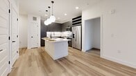 Located at 2908 East Howard Lane in Manor, TX, this well-appointed 2-bedroom, 2-bathroom single-floor home combines modern design with functional living. Light wood-tone flooring flows consistently throughout, creating a cohesive and airy aesthetic across every room.

The kitchen serves as the centerpiece of the home, featuring a large white quartz center island with an undermount sink and dishwasher, bold charcoal-gray shaker cabinetry with black hardware, under-cabinet lighting, and stainless steel appliances including a refrigerator, range, and microwave. Globe pendant lights suspended from black fixtures add a contemporary finishing touch overhead.

Both bedrooms are bright and well-sized, with large windows dressed in white blinds that invite generous natural light and offer views of the surrounding neighborhood. Ceiling fans are present in the bedrooms for added comfort. The primary bedroom connects to a well-designed en-suite bathroom featuring a dual-sink vanity with gray cabinetry, white countertops, a large mirror with vanity lighting, and black hardware accents.

The second bathroom includes a soaking tub with shower and a matching gray vanity. The home also offers an impressive five closets, providing abundant storage throughout. A private balcony extends the living space outdoors, completing this thoughtfully designed residence.