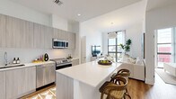 Located in Miami's Coconut Grove neighborhood, this contemporary 2-bedroom, 2-bathroom residence offers a thoughtfully designed open-concept layout with modern finishes throughout. The kitchen serves as a central hub, featuring flat-front cabinetry in a warm gray wood tone, quartz countertops, stainless steel appliances including a French door refrigerator, built-in microwave, range, and dishwasher, and a generous island with seating — ideal for casual dining and entertaining. The kitchen flows seamlessly into the living area, which is anchored by floor-to-ceiling windows that flood the space with natural light and frame open city views. Wide-plank hardwood flooring runs throughout the main living areas, adding warmth to the bright, neutral palette. The primary bedroom continues the floor-to-ceiling window theme, offering abundant natural light and sweeping views of the Miami skyline. It includes a built-in closet and is complemented by a sleek en-suite bathroom with a glass-enclosed walk-in shower, floating vanity, and quartz countertop. The second bathroom features a full tub-shower combination with subway tile surround and a matching quartz vanity. Both bedrooms are well-proportioned with ample closet storage, creating a comfortable and functional living environment in the heart of Miami.