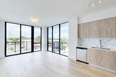 Located at 4465 Griffin Rd in Hollywood, FL, this modern 3-bedroom, 2-bathroom residence offers a thoughtfully designed single-floor layout with clean, contemporary finishes throughout. The open-concept living, dining, and kitchen area is anchored by dramatic floor-to-ceiling windows that flood the space with natural light and provide direct access to a private balcony with open city views. The kitchen features light wood cabinetry, a marble-look tile backsplash, white quartz countertops, a stainless steel dishwasher, and a sleek undermount sink. Light-toned hardwood flooring runs seamlessly throughout the living areas and bedrooms, enhancing the bright, airy ambiance. The primary bedroom offers a generous footprint with ample closet space. In total, five closets provide exceptional storage across the residence. The bathrooms are finished with modern dual-sink vanities, wood cabinetry, large mirrors, and marble-tiled walk-in showers. A dedicated laundry area houses a stacked washer and dryer unit for added convenience. A hallway connects the private quarters, maintaining a clear separation between living and sleeping areas. The overall aesthetic is minimalist and contemporary, with crisp white walls, black hardware accents, and an abundance of natural light defining every room.