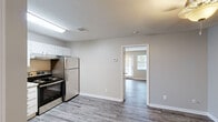 This single-floor unit on Park Lake Road in Fort Oglethorpe, Georgia, presents a clean and functional layout finished with consistent, neutral tones throughout. Wood-look plank flooring runs across the main living areas, providing a cohesive and low-maintenance surface underfoot.

The kitchen is a standout feature, outfitted with white cabinetry offering ample upper and lower storage, light granite-style countertops, and a full suite of stainless steel appliances including a range, refrigerator, and dishwasher. A single-basin sink with a brushed nickel faucet completes the workspace. Overhead fluorescent lighting keeps the kitchen bright and practical.

The kitchen opens toward a separate living area, visible through a doorway and benefiting from natural light admitted by a window near the entry door. The living space is open and versatile, with neutral beige walls, textured ceilings, and ample room for a variety of furniture arrangements.

The bathroom is finished in white and neutral tones, featuring a tub-shower combination, a white vanity with an integrated sink, and a large mirror with overhead lighting. The space is simple, clean, and well-appointed. Overall, the unit maintains a fresh, move-in-ready character with consistent finishes throughout.