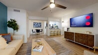 Located at 8445 Gardens Cir in Sarasota, Florida, this single-story residence offers a thoughtfully designed open-concept floor plan with a cohesive, contemporary aesthetic. Light-toned wood-look flooring flows throughout the main living areas, creating a bright and airy atmosphere.

The living room serves as the heart of the home, highlighted by a bold teal accent wall, ceiling fan, and large sliding glass doors that invite abundant natural light and provide direct access to the screened patio. The patio offers a comfortable outdoor retreat with tree-lined views. The living area connects seamlessly to the dining space and kitchen, making it ideal for both everyday living and entertaining.

The kitchen is outfitted with white cabinetry, granite countertops, stainless steel appliances — including a range, microwave, refrigerator, and dishwasher — and a breakfast bar with stylish gold-toned stools.

The bedrooms are carpeted for comfort and feature soft, neutral tones. The bathrooms are clean and modern, each equipped with white shaker-style vanities, granite countertops, tub-shower combinations with tiled surrounds, and wood-look flooring.

Throughout the space, a coastal-inspired color palette of blues, whites, and warm wood tones creates a relaxed yet refined ambiance perfectly suited to the Sarasota lifestyle.
